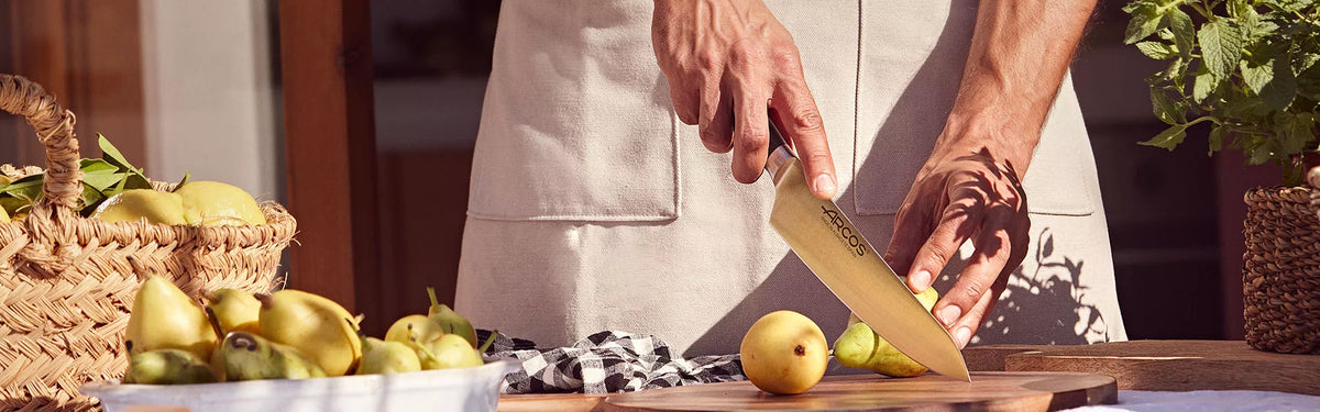 Banner cocinero cortando con un cuchillo cocinero de la serie clara una pera en una tabla de madera